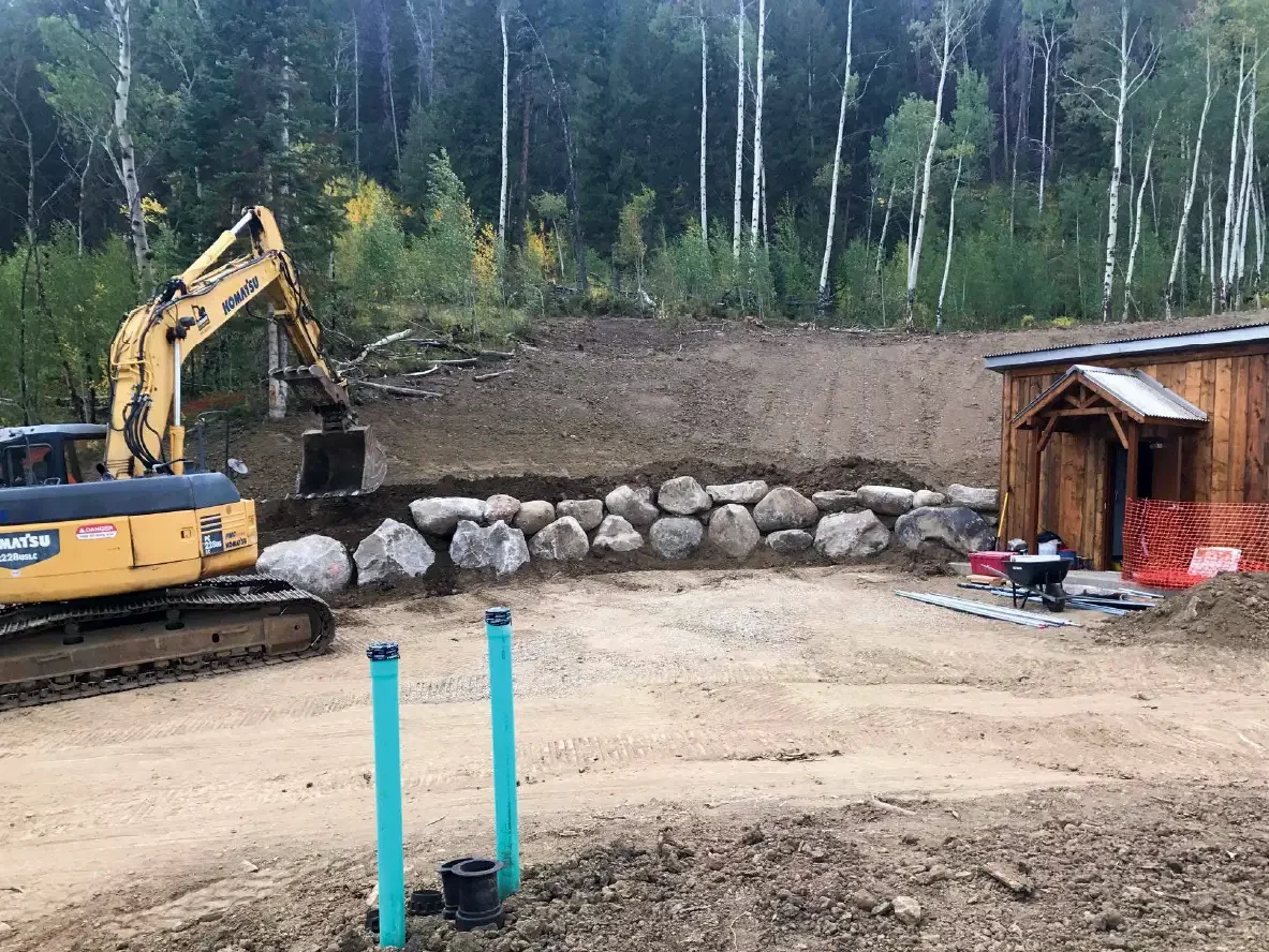 A construction site at C Lazy U Ranch featuring a small building and a large excavator at the site of their main water treatment facility for drinking water.